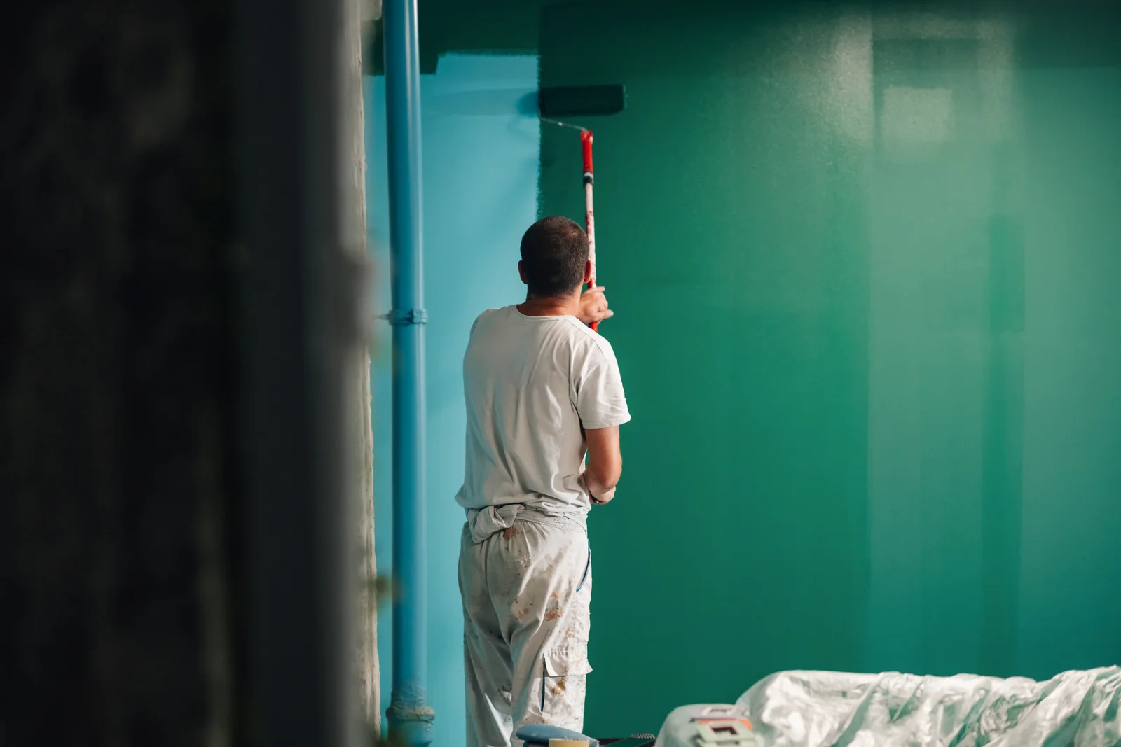 Pintor dando color a una pared con rodillo en una vivienda de Mutilva