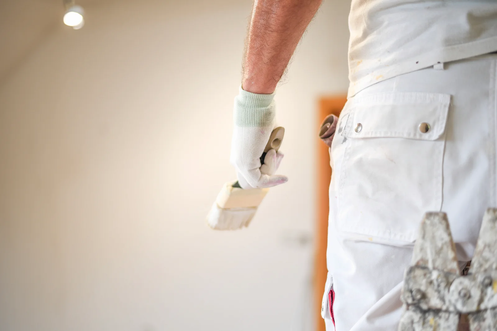 Pintor con escalera y bote de pintura preparando una habitación